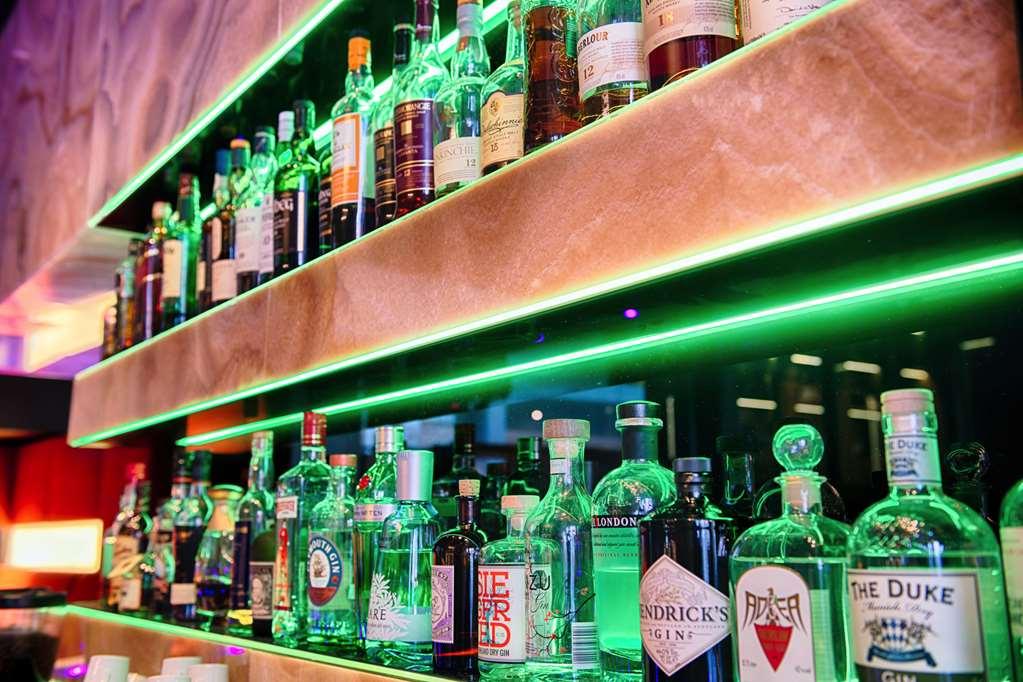 Steigenberger Hotel Am Kanzleramt Berlin Restaurant foto The photo depicts a well-organized display of various bottles of alcoholic beverages arranged on shelves. The shelves are illuminated with green lighting, enhancing the visual appeal of the setup. The bottles include a mix of spirits such as gin, whi