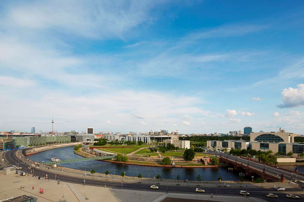 Steigenberger Hotel Am Kanzleramt Berlin Exterior foto The photo depicts a panoramic view of a cityscape featuring a river that winds through the landscape. On one side of the river, there are green spaces with trees and grass, suggesting an area designed for leisure or parks. Along the riverbank, you ca