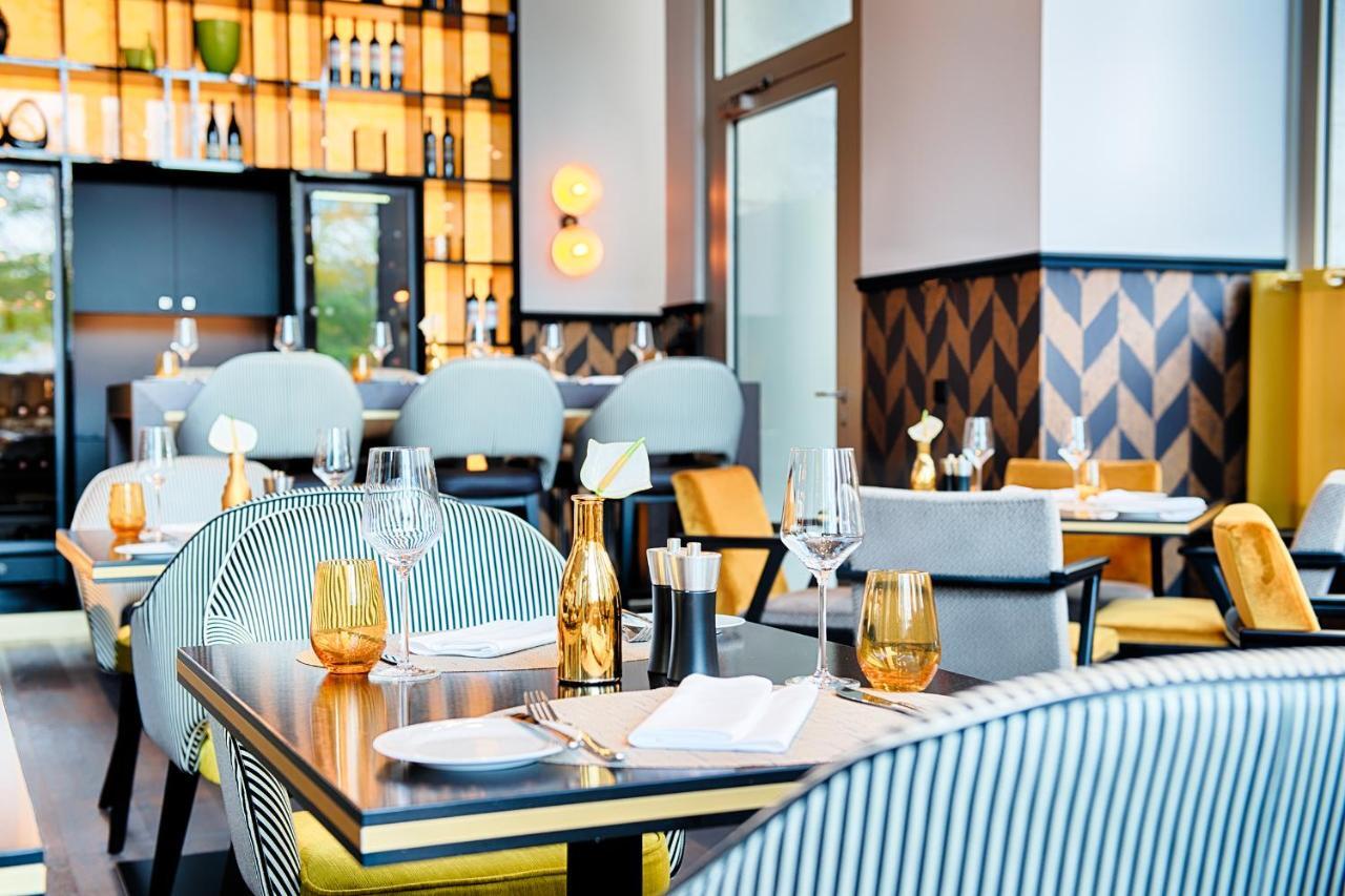 Steigenberger Hotel Am Kanzleramt Berlin Exterior foto The photo showcases a modern restaurant interior. The design features a mix of stylish seating, with chairs and tables arranged for dining. The color palette incorporates soft tones, including gray and vibrant yellow. There are elegant glassware and 